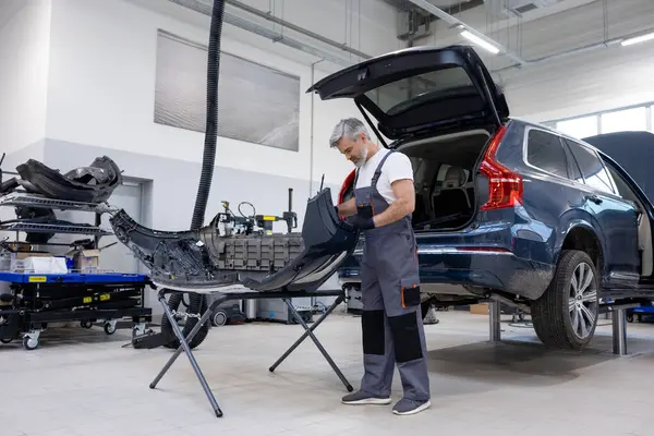 Sakallı otomotiv işçisi atölyede güvenlik için kontrol ve kontrol yapıyor.