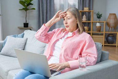 Menopoz. Pembe gömlekli orta yaşlı kadın kendini iyi hissetmiyor ve başı ağrıyor.