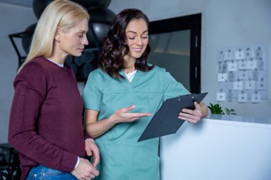 Teşhis sonuçları. Esmer genç doktor teşhis sonuçları hakkında bir kadın hastayla konuşuyor.