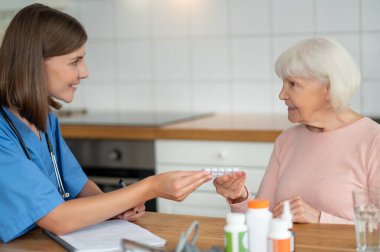 Evde bakım hemşiresi, kıdemli hastaya yardım ediyor. İlaç alıyor, tedavi görüyor ve hastalık tedavisine destek veriyor.