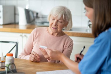 Tıbbi uzman, yaşlı hastalara hastalık tedavisi ve ilaç ve ilaç sağlamada yardım sunuyor