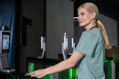 Giriş kartını kullanarak. Laboratuar önlüklü kadın doktor giriş kartını kullanarak güvenlik kontrolünden geçiyor.