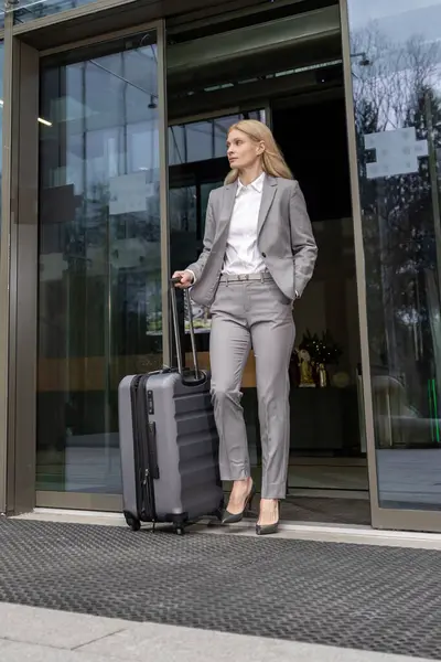 Zarif bayan gezgin profesyonel iş seyahati için bavullarıyla havaalanına geliyor.