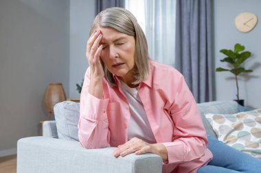 Baş ağrısı. Orta yaşlı kadın baş ağrısı çekiyor ve bitkin görünüyor.