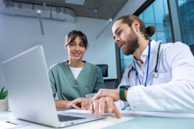 Klinikte MSN doktoruyla çalışan kadın pratisyen hasta verilerini analiz etmek ve tıbbı tartışmak için bilgisayar kullanıyor.