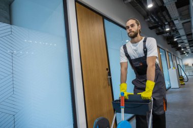 İş yerine gidiyorum. Üniformalı genç adam ofis koridorunda yürüyor ve arabayı itiyor.