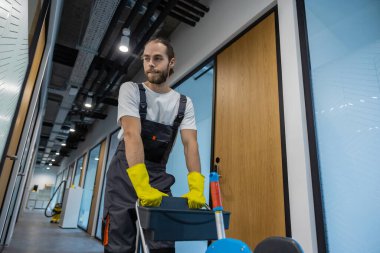 İş yerine gidiyorum. Üniformalı genç adam ofis koridorunda yürüyor ve arabayı itiyor.