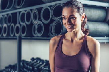 Spor salonundaki kadın. Hoş, genç, siyah saçlı bir kadın. Keyifli görünüyor. Spor salonunda vakit geçiriyor.