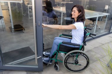 Ofise giriyorum. Ofis girişinde tekerlekli sandalyedeki siyah saçlı kadın.