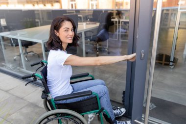 Ofise giriyorum. Ofis girişinde tekerlekli sandalyedeki siyah saçlı kadın.
