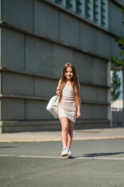 Sırtında sırt çantasıyla gezen mutlu okul kızı güneşli yaz gününün tadını çıkarıyor.