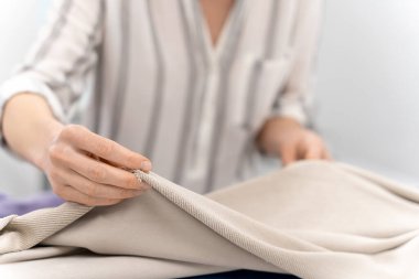 Kumaşla çalış. Moda tasarımcısı tasarım stüdyosunda çalışırken kumaşı elinde tutuyor.