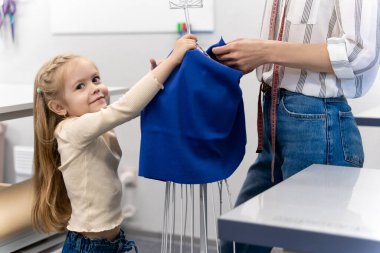 Dikiş salonu. Küçük tatlı kız dikiş salonunda annesine yardım ediyor.