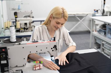 Moda tasarımcısı. Stüdyosunda çalışan ve gülümseyen genç bir moda tasarımcısı.