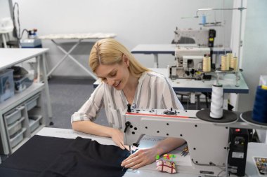 Moda tasarımcısı. Stüdyosunda çalışan ve gülümseyen genç bir moda tasarımcısı.