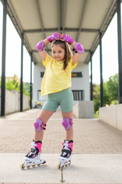 Küçük bayan patenci dışarıda paten sürerken eğleniyor paten becerilerini geliştiriyor.