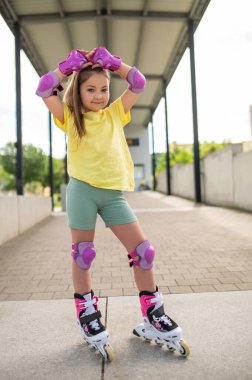 Stadyumun dışında buz pateni yapan küçük kız sağlıklı yaz aktivitelerinin tadını çıkarıyor.