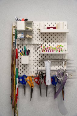 Dikiş aletleri. Duvar raflarında renkli makas ve ölçü bantları