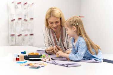 Küçük tasarımcı. Şirin sarışın çocuk tasarım stüdyosunda yeni bir modeli kesiyor.