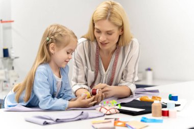 Dikiş iplikleri. Anne ve çocuk dikiş dikmek için iplik seçerken meşgul görünüyorlar.