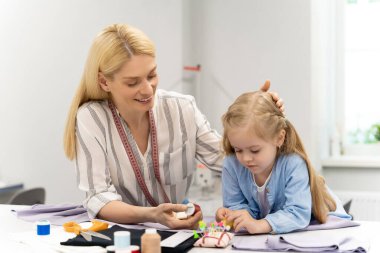 Dikiş iplikleri. Anne ve çocuk dikiş dikmek için iplik seçerken meşgul görünüyorlar.