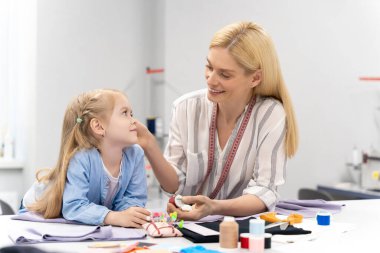 Dikiş iplikleri. Anne ve çocuk dikiş dikmek için iplik seçerken meşgul görünüyorlar.
