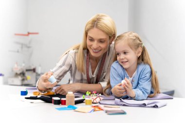 Dikiş iplikleri. Anne ve çocuk dikiş dikmek için iplik seçerken meşgul görünüyorlar.