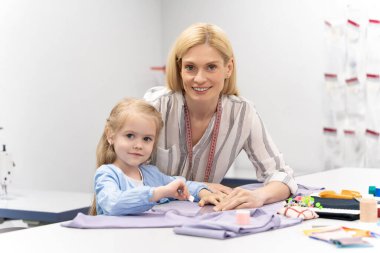 Elbise tasarımı. Anne ve kızı tasarım stüdyosunda birlikte vakit geçiriyorlar ve memnun görünüyorlar.