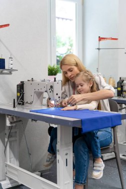 Dikiş dikiyorum Anne ve kızı dikiş makinesinde birlikte oturuyorlar ve meşgul görünüyorlar.