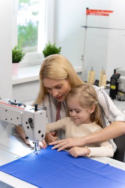 Dikiş dikiyorum Anne ve kızı dikiş makinesinde birlikte oturuyorlar ve meşgul görünüyorlar.