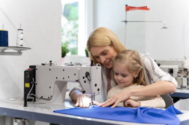 Dikiş dikiyorum Anne ve kızı dikiş makinesinde birlikte oturuyorlar ve meşgul görünüyorlar.