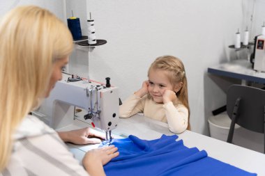 Kıyafet tasarımcısı stüdyosu. Sevimli küçük kız annesiyle bir tasarımcı stüdyosunda vakit geçiriyor.