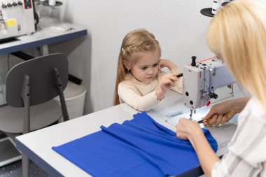 Kıyafet tasarımcısı stüdyosu. Sevimli küçük kız annesiyle bir tasarımcı stüdyosunda vakit geçiriyor.