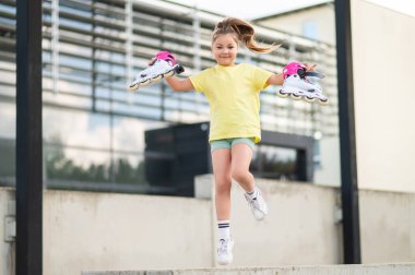 Küçük kız paten kaymadan önce eğlenceli aktivitelerin keyfini çıkarıyor stadyumda patinaj becerileri geliştiriyor.
