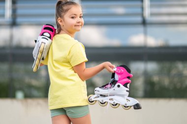 Dışarıda patenlerle oynayan enerjik bayan çocuk yaz tatilinin tadını çıkarıyor.