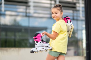 Aktif çocuk dışarıda paten kayıyor. Oyun saatlerinde ustalaşıyor. Paten kayıyor.