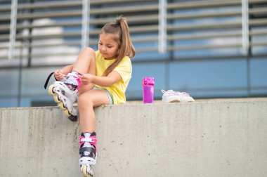 Paten giyen, tokaları takan, aktif paten ve oyun saatine hazırlanan kadın çocuk.