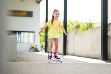 Aktif çocuk dışarıda paten sürüyor, eğleniyor ve enerjik oyunlar oynuyor.