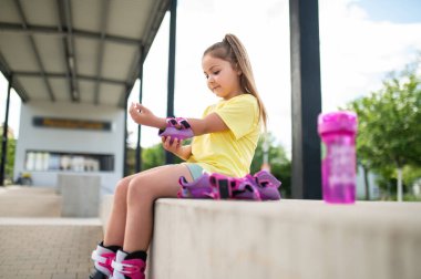 Patenci çocuk emniyet teçhizatını ayarlıyor paten kaymaya hazırlanıyor.