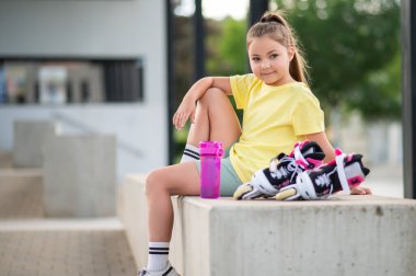 Kız dışarıda paten kaymaya hazırlanıyor. Aktif yaz sporlarının ve antrenmanların tadını çıkarıyor.