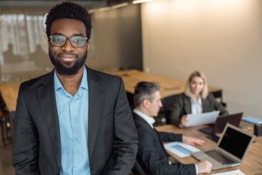 Ofiste. Zarif Afro-Amerikan iş adamı iş arkadaşlarıyla birlikte ofiste.