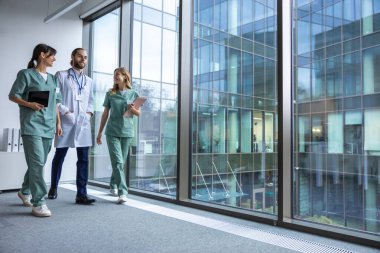 Klinikte. Laboratuvar önlüklü bir grup genç doktor klinik koridorunda yürüyor ve konuşuyorlar.
