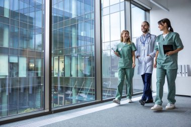 Klinikte. Laboratuvar önlüklü bir grup genç doktor klinik koridorunda yürüyor ve konuşuyorlar.