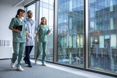 Klinikte. Laboratuvar önlüklü bir grup genç doktor klinik koridorunda yürüyor ve konuşuyorlar.