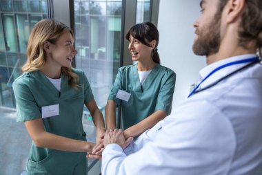 Arkadaşlık. Bir grup doktor el ele tutuşup olumlu bakıyor ve gülümsüyor.