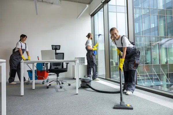 Ofiste hijyen var. Oda servisi konferans odasını temizliyor ve meşgul ve ilgili görünüyor.