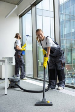 Ofiste hijyen var. Oda servisi konferans odasını temizliyor ve meşgul ve ilgili görünüyor.