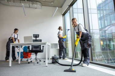 Ofiste hijyen var. Oda servisi konferans odasını temizliyor ve meşgul ve ilgili görünüyor.