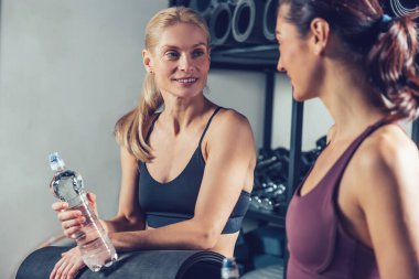 Antrenmandan sonra. Spor giyimli genç kadınlar spor salonunda idmandan sonra dinleniyorlar.