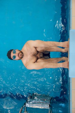 Yüzücü. Yüzme gözlüklü bir adam havuzda egzersiz yapıyor.
